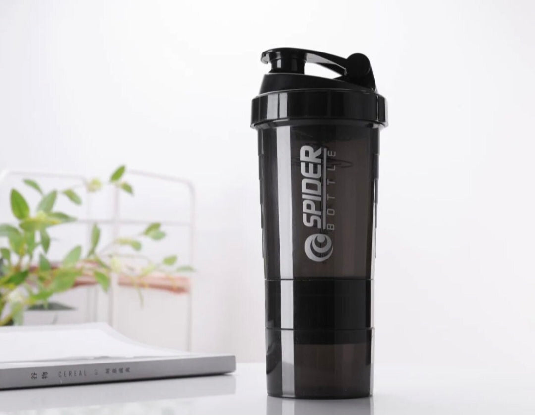 Black shaker bottle with 'Spider Bottle' logo on a white surface with a plant in the background