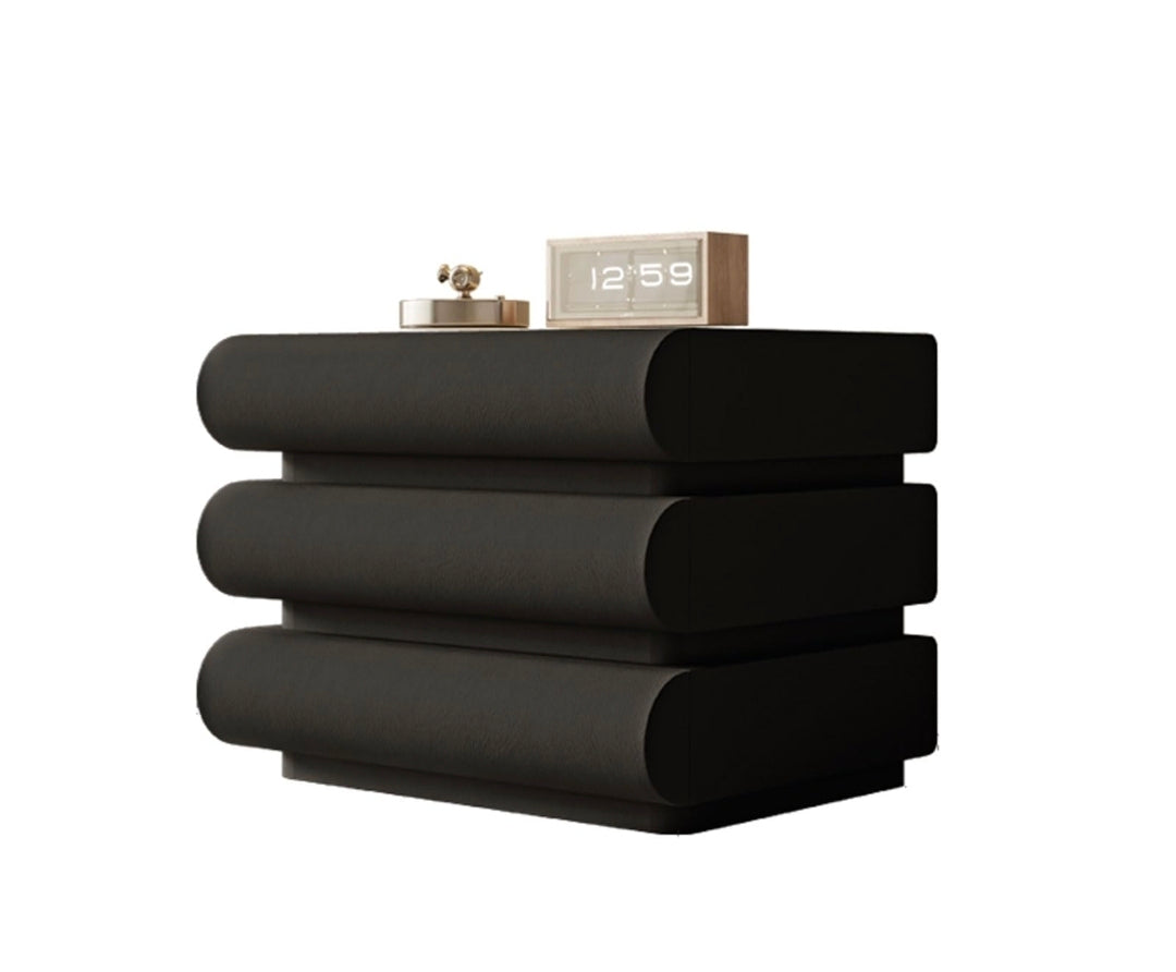 Stack of black towels with a silver alarm clock on a white background