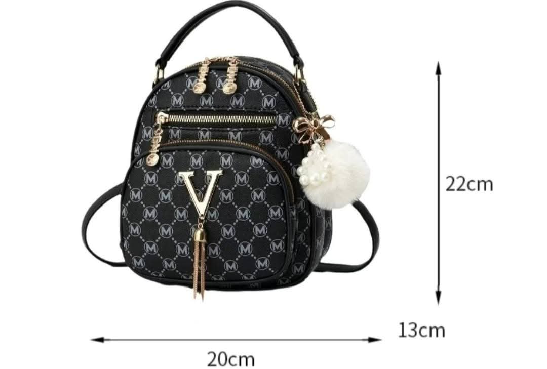 Black monogram mini backpack with gold-tone hardware, a white pom-pom charm, and dimension arrows showing 20cm width, 13cm height, and 22cm depth on a white background.
