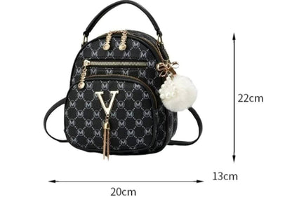 Black monogram mini backpack with gold-tone hardware, a white pom-pom charm, and dimension arrows showing 20cm width, 13cm height, and 22cm depth on a white background.