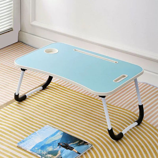 Foldable laptop desk on a striped rug with a magazine underneath
