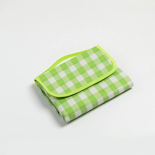 Folded green and white checkered picnic blanket on a light gray background