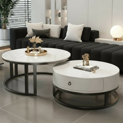 Modern living room with black sofa, round white coffee tables, and decorative items.