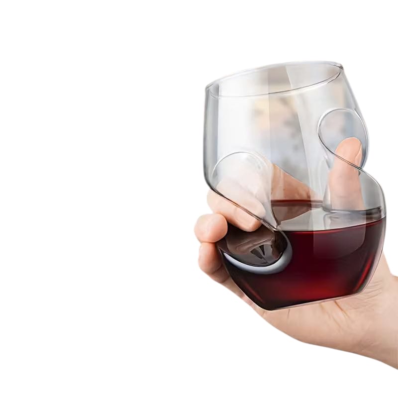 Hand holding a wine glass with a unique design, featuring a small round object inside.