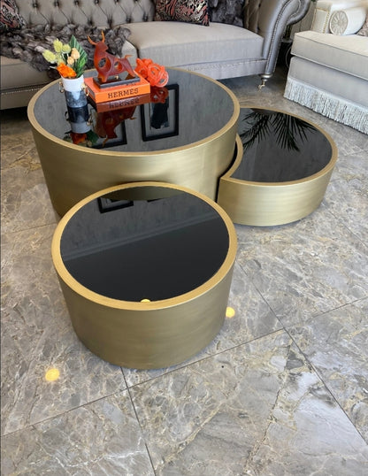 Set of gold and black round tables on a marble floor with a gray sofa in the background.