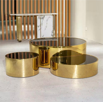 Set of gold metal tables on a light gray floor with a wooden wall in the background