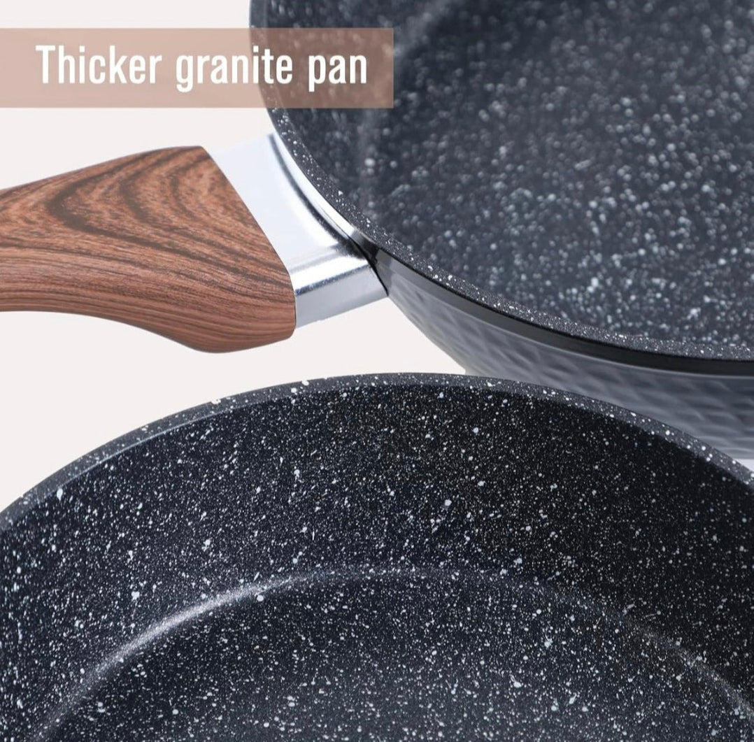 Close-up of a granite cookware set with a wooden handle on a light background.