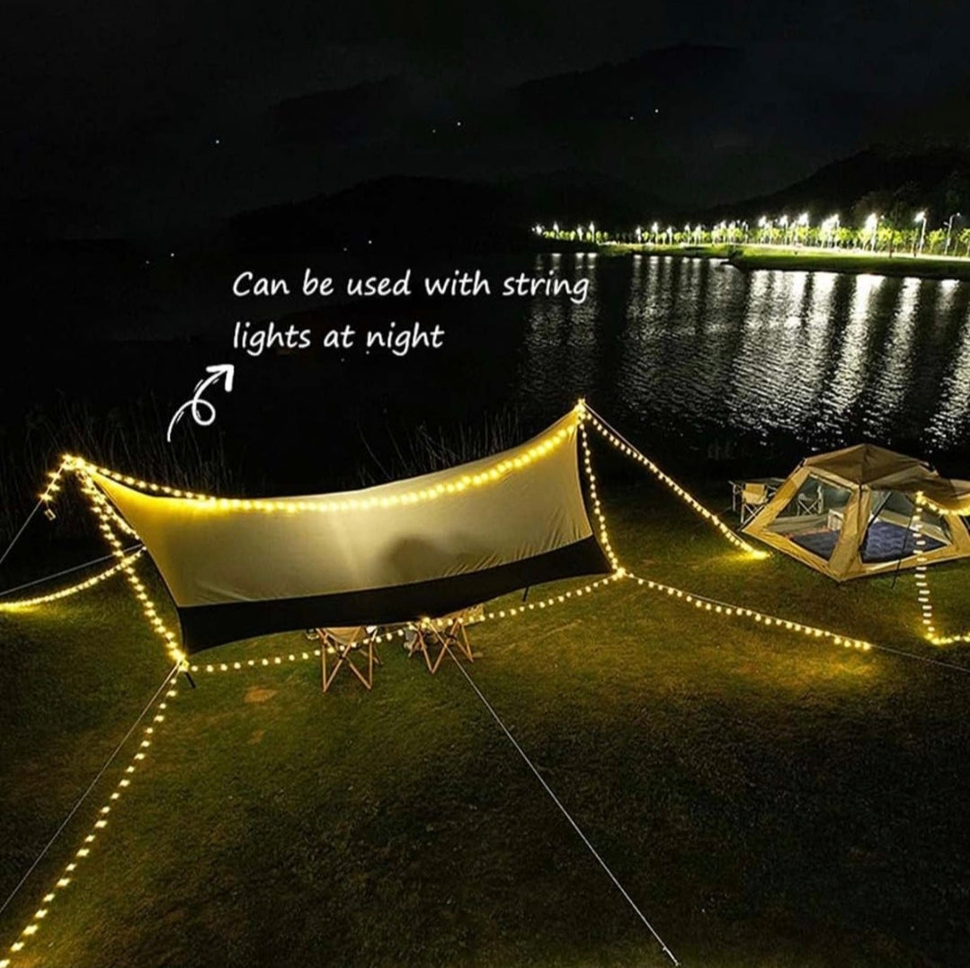 Outdoor setup with a canopy and string lights near a body of water at night.